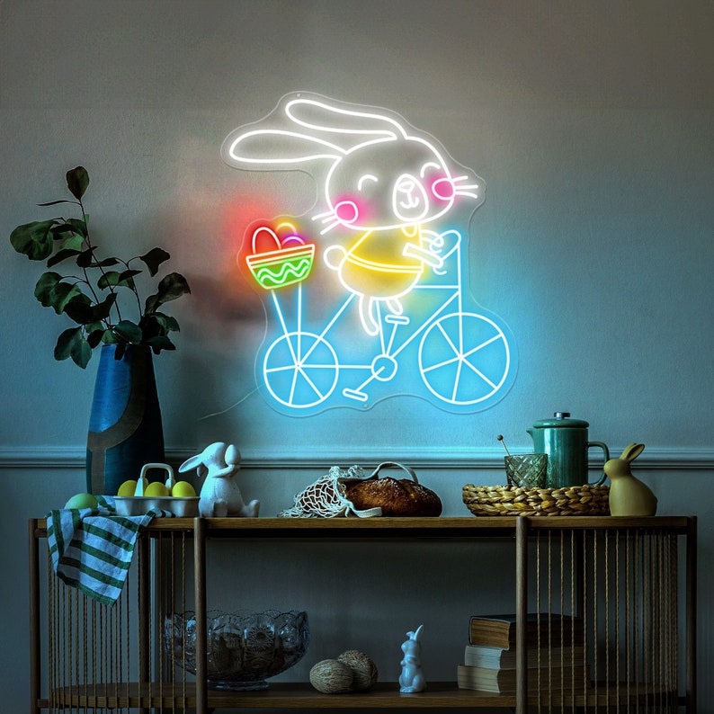 Bunny on Bike Easter LED neon sign glowing on wall with playful bunny riding a bike design for home decor, nursery, party, or shop display by Neon.Shop.