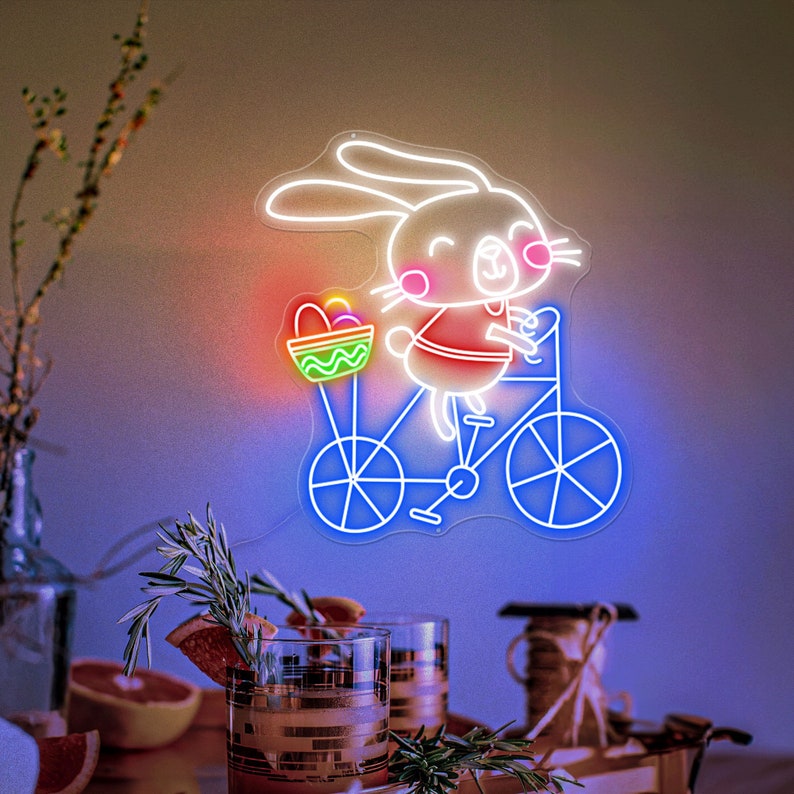 Bunny on Bike Easter LED neon sign glowing on wall with playful bunny riding a bike design for home decor, nursery, party, or shop display by Neon.Shop.