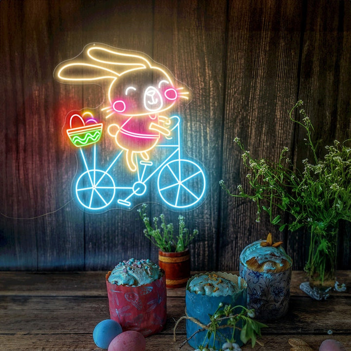 Bunny on Bike Easter LED neon sign glowing on wall with playful bunny riding a bike design for home decor, nursery, party, or shop display by Neon.Shop.