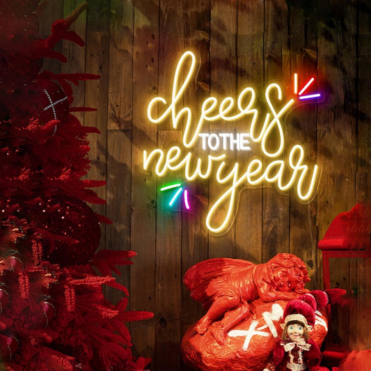 Cheers to the New Year' LED neon sign in warm white script font, mounted on a dark wall by Neon.Shop.