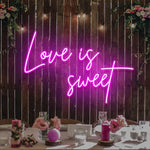 Love Is Sweet Valentine’s Day neon sign glowing in warm LED lights, romantic wall décor by Neon.Shop