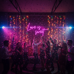 Love Is Sweet Valentine’s Day neon sign glowing in warm LED lights, romantic wall décor by Neon.Shop