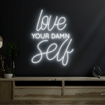 Love Your Damn Self LED neon sign by Neon.Shop glowing on a modern wall as bold and inspirational neon décor
