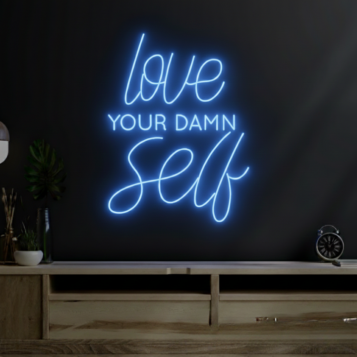 Love Your Damn Self LED neon sign by Neon.Shop glowing on a modern wall as bold and inspirational neon décor
