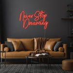 Never Stop Dreaming LED neon sign by Neon.Shop glowing on a modern interior wall as inspirational neon wall decor