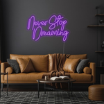 Never Stop Dreaming LED neon sign by Neon.Shop glowing on a modern interior wall as inspirational neon wall decor