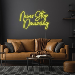 Never Stop Dreaming LED neon sign by Neon.Shop glowing on a modern interior wall as inspirational neon wall decor