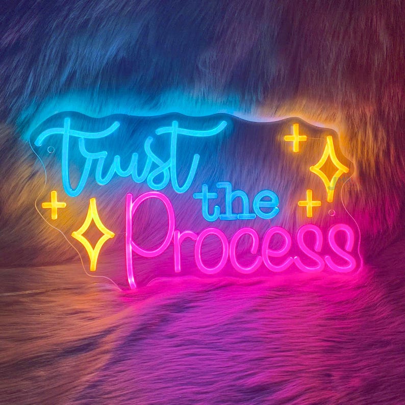 Trust The Process” neon sign illuminating a workspace, encouraging focus and perseverance by Neon.Shop.