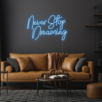 Never Stop Dreaming LED neon sign by Neon.Shop glowing on a modern interior wall as inspirational neon wall decor
