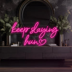 Keep Slaying Hun’ LED neon sign glowing brightly, ideal for beauty salons, glam rooms, and empowering home décor by Neon.Shop